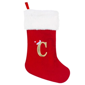Close-up of red velvet Christmas stocking with white plush trim and golden glitter letter C