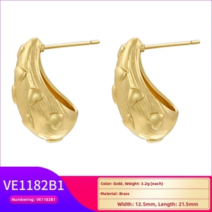 Detail of J-shaped gold-plated brass stud earrings with embossed heart pattern texture