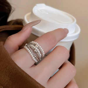 Detail of multi-layer pearl ring with silver accents on model holding coffee cup