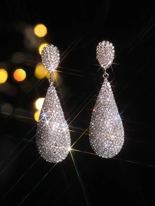 Macro shot of luxury silver teardrop earrings with sparkling rhinestones and bokeh effects