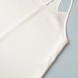 Detail of white satin camisole dress showing smooth silk texture and fine neckline edging