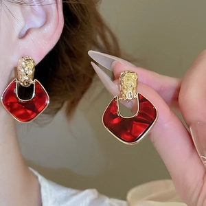 Detail of gold hammered metal and red translucent resin geometric drop earrings