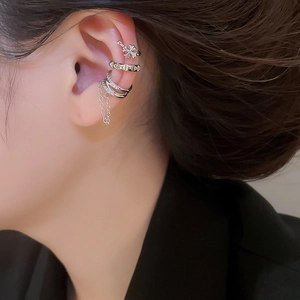 Detailed view of silver cuff earrings set with cross stud and hanging tassel chain
