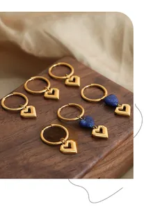 Detailed view of hollow heart pendant earrings with gold hoops and blue natural stones