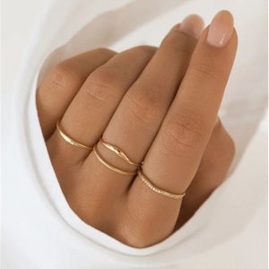 Close-up of elegant gold wavy rings and crystal studded bands on model fingers