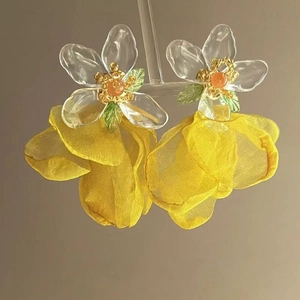 Détail de boucles d'oreilles fleur avec pétales en mousseline jaune et acrylique