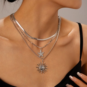 Detail of layered silver necklaces with snake chain, starfish and sun face pendants