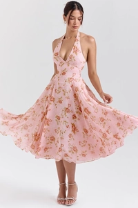 Detail of pink halter neck midi dress featuring orange floral patterns and a flowy hemline