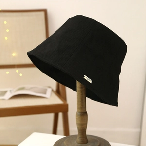 Vue détaillée d'un chapeau bob noir avec logo en métal argenté sur support en bois
