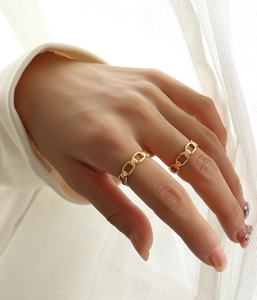 Detail showing two gold chain rings with minimalist links worn on fingers