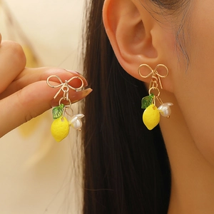 Sweet yellow lemon fruit earrings with gold bow and green leaf on female model