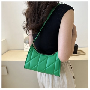 Detail of green quilted baguette shoulder bag showing leather texture and stitching