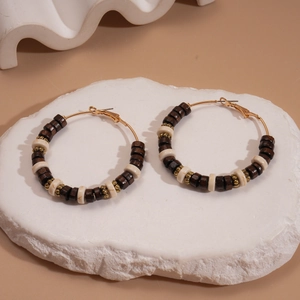 Bohemian wood bead hoop earrings with golden metal rings on a white stone pedestal
