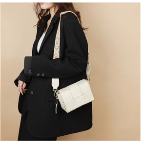 Close-up of white woven leather crossbody bag with geometric pattern wide strap