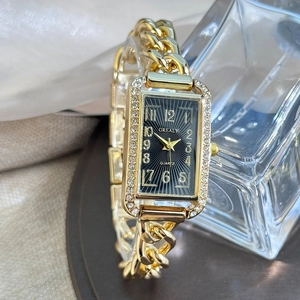 Detail of a square gold chain watch for women featuring a black dial and diamond bezel