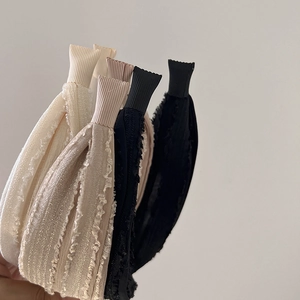 Close-up of three beige, khaki, and black fabric headbands with lace and pleated textures
