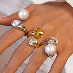 Detailed view of layered rings featuring pearls and crystals worn on model's hand