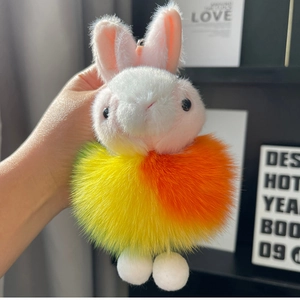 Close-up of plush rabbit keychain with colorful gradient fur ball and metal clasp