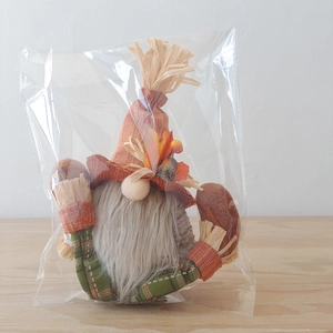 Close-up of autumn gnome doll with straw hat and maple leaves on a wooden table