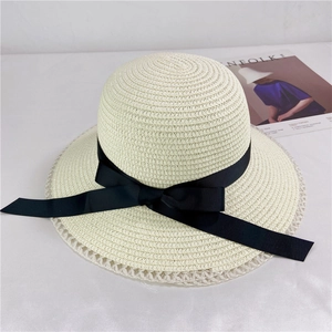 Close-up of woven straw sun hat with black bow ribbon and delicate lace brim detail
