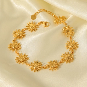 Detail of 18K gold stainless steel sun anklet displayed on premium beige silk fabric