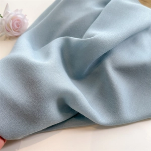 Detail shot of light blue cotton linen scarf fabric with soft texture and natural folds