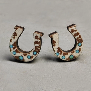 Macro detail of wooden horseshoe stud earrings with faux cowhide print and turquoise dots