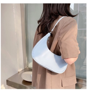 Side view of light blue nylon crescent shoulder bag worn by model in minimalist setting