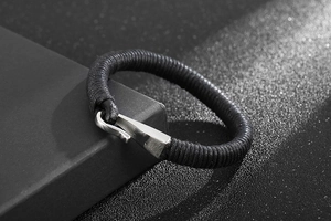 Macro view of woven black leather rope bracelet with polished silver hook clasp