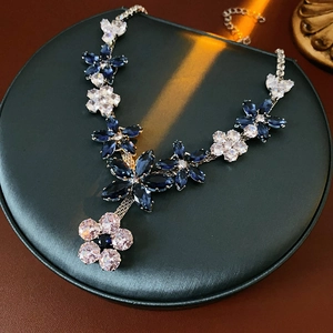 Detailed view of silver flower necklace set with blue and white zircon on black display