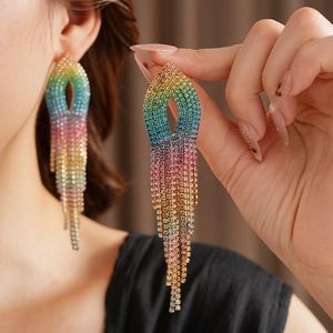 Close-up of rainbow gradient rhinestone tassel earrings worn by a model in soft lighting