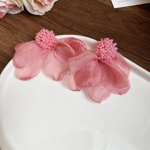 Detail of pink fabric flower earrings with beaded center on a ceramic plate