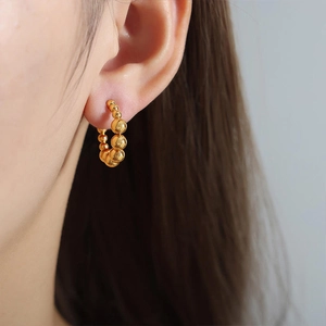 Detail of gold beaded hoop earring featuring a gradient size bead design on the ear
