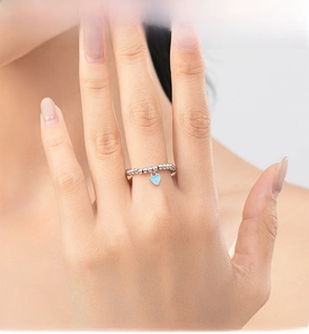 Detail of S925 silver beaded ring featuring a light blue enamel heart pendant on hand