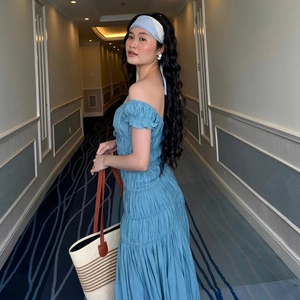 Détail d'une robe bleue à épaules dénudées avec des volants plissés et un tissu texturé