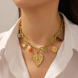 Golden chain and green cord necklace with sun and heart charms worn by a model