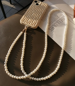 Detail showing creamy white grooved phone case with long faux pearl crossbody strap
