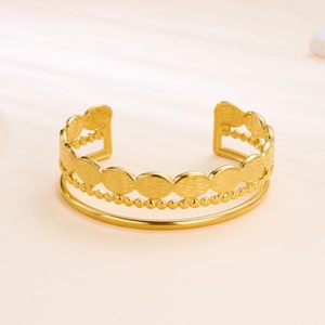 Macro detail of gold-plated geometric layered bangle with textured oval patterns