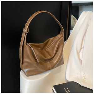 Detail of adjustable strap and smooth coffee faux leather texture on hobo tote bag
