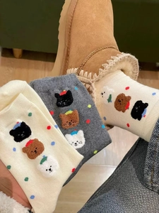 Dettaglio di calzini in cotone ricamati con gatto e orso nei colori beige e grigio