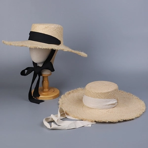 Detailed view of raffia sun hats with frayed edges and wide fabric ribbons on stands