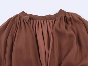 Detail view of brown chiffon fabric with pleated neckline and soft vertical texture