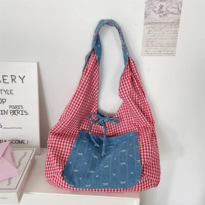 Detail of red checkered tote bag with denim pocket featuring white bow patterns