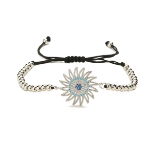 Vue macro d'une breloque tournesol aux cristaux bleus et bracelet en cordelette ajustable
