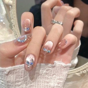 Gros plan d'ongles rose gold œil de chat avec paillettes en forme de papillon et de lune