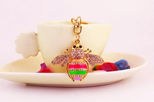 Macro detail of bee keychain featuring colorful enamel stripes and sparkling crystal wings