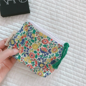 Close-up of floral cotton mini pouch with zipper and green woven strap detail