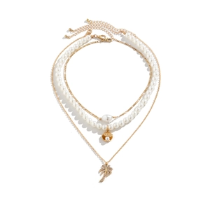 Detailed close-up of triple-layered gold necklace with pearl beads and coconut tree pendant