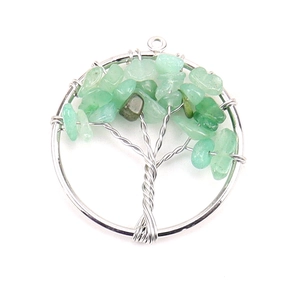 Macro shot of silver tree of life pendant with green natural crystal stones on white base