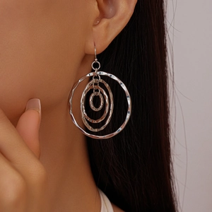 Detail of silver layered concentric hoop earrings with hammered texture on female model